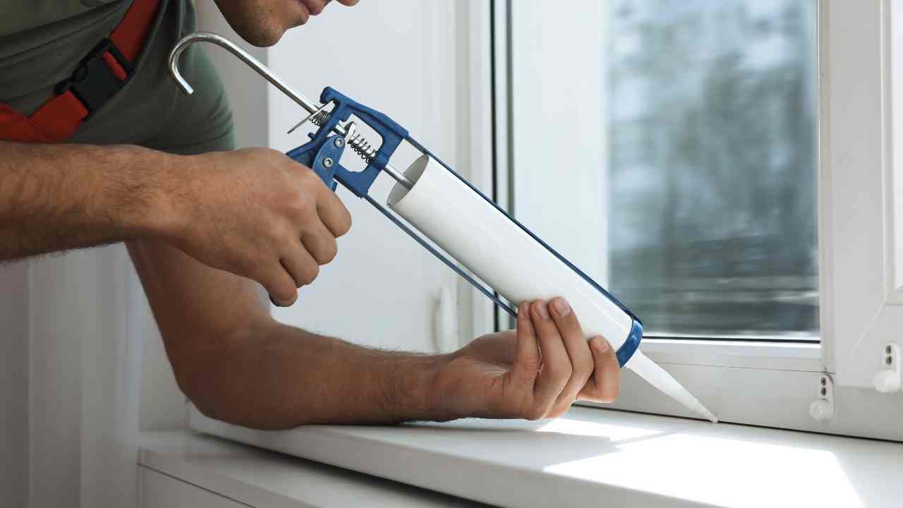 person sealing a window to prevent water damage